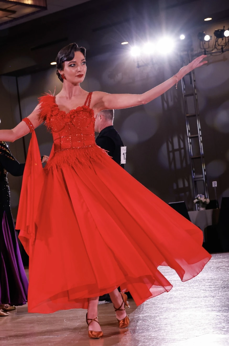 Ballroom dancer wearing the red Crimson Reverie gown in competition