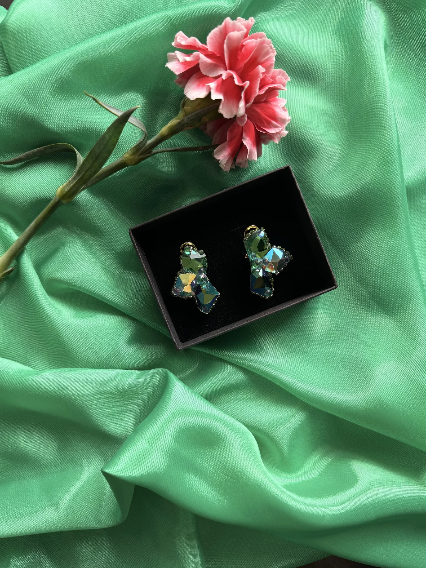 Aurora crystal earrings presented on green satin