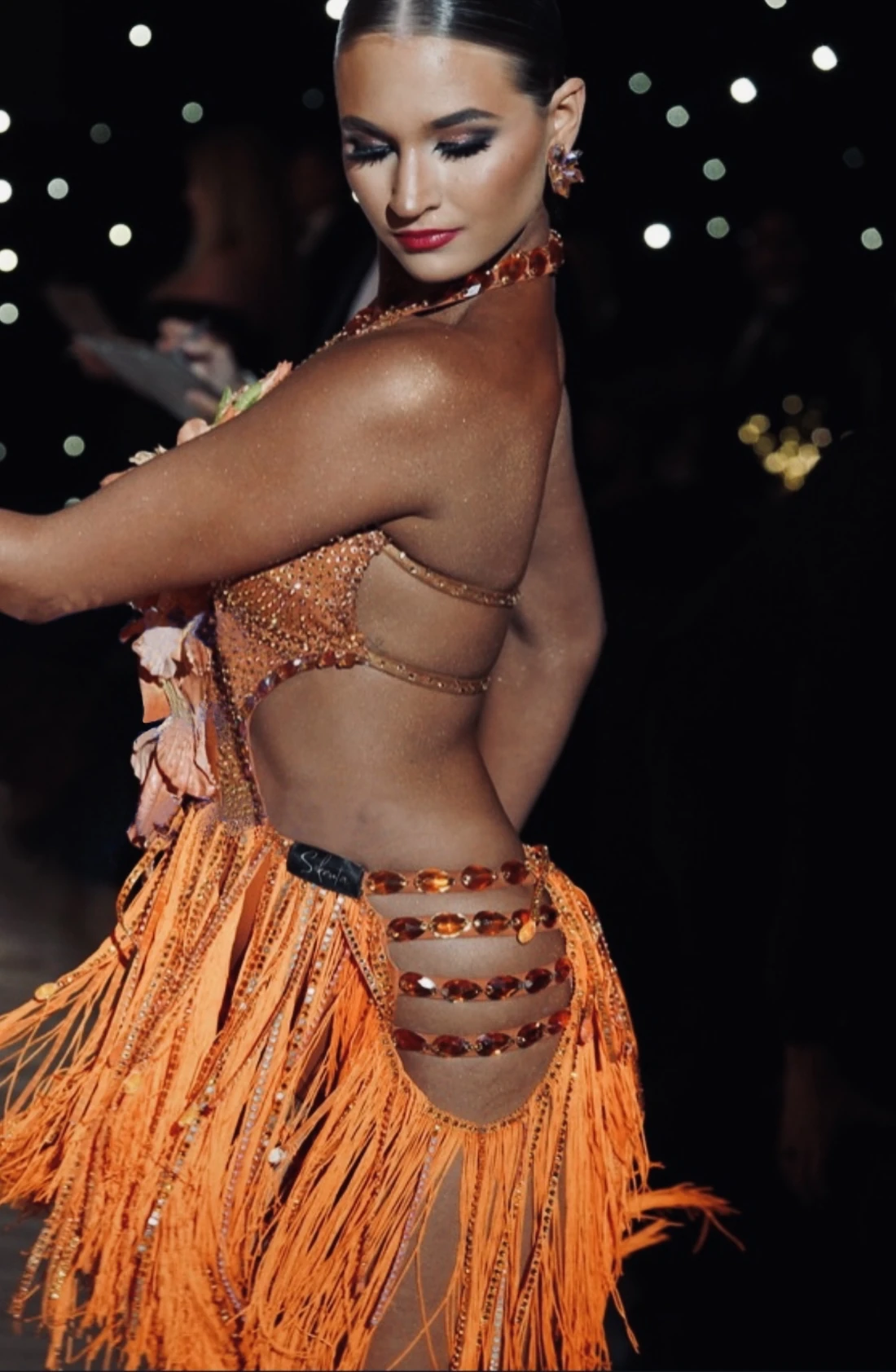 Ballroom dancer in an orange crystal and fringe dress